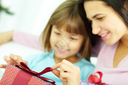 母亲和女儿在礼物盒上绑带丝图片