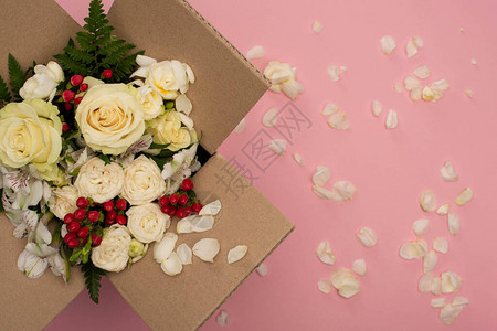 在粉红色背景散落的花瓣附近在纸板盒图片