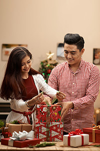 圣诞节庆典的年轻亚洲夫妇包礼物图片