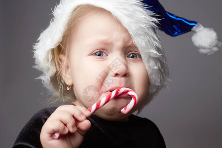 哭泣的婴儿圣诞老人的小女孩棒糖果的孩子圣诞节时悲伤的图片