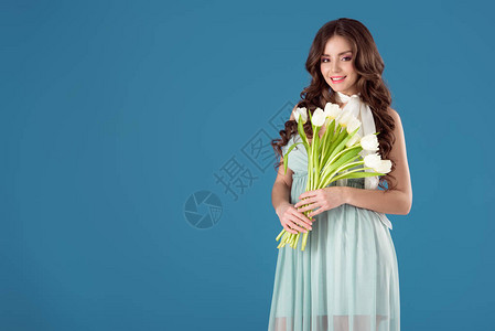 穿着一束郁金香花的快乐女孩看着蓝色图片