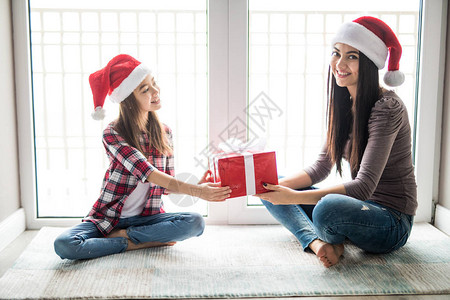 幸福的母亲和女儿戴着圣诞老人的帽子图片