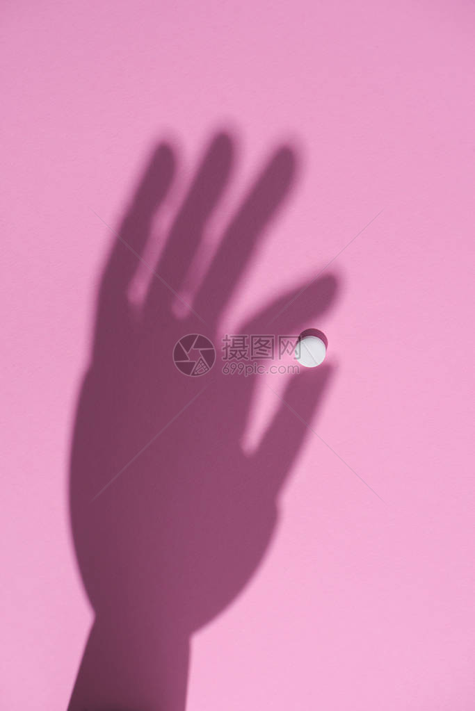 粉红色表面握有白药片的手图片