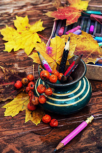 有彩色铅笔和秋叶的花瓶图片