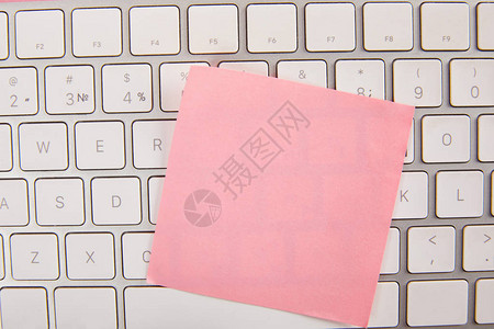 膝上型计算机键盘上的空粉红色粘贴笔背景图片
