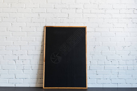 木框里的空黑板站在白砖墙上背景图片