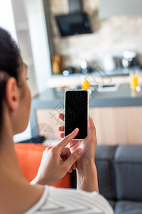 厨房内用带空白屏幕的智能手机的妇女有图片
