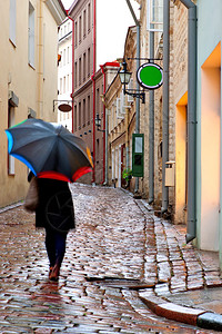 在爱沙尼亚塔林的狭小街道上带着雨伞和图片