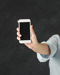 无法辨认的女人在黑色背景下显示带空白屏幕的智能手机移动应用图片