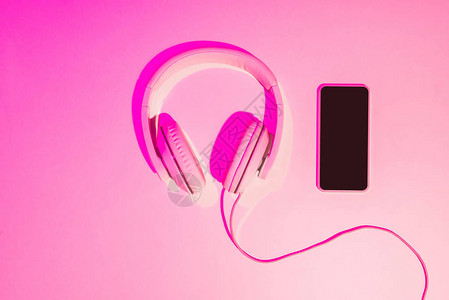 粉红色背景中带耳机的智能手机的粉背景图片