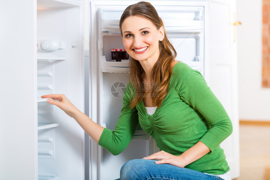 年轻的妇女或管家或女管家解冻冰箱图片