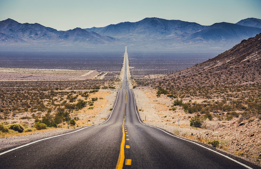 一条无尽的直路穿过美国西南部贫瘠的风景的经典全景图图片