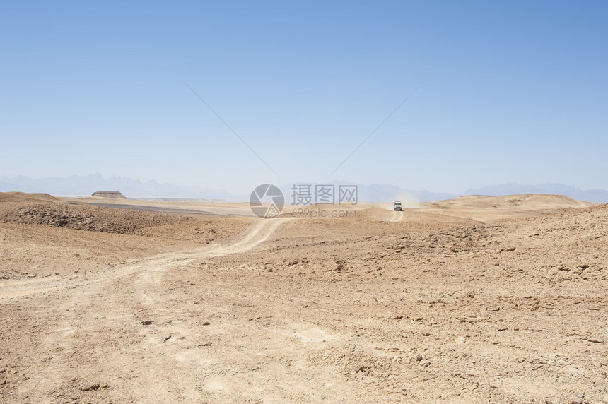 在荒漠的荒漠地貌上乘坐越野车图片