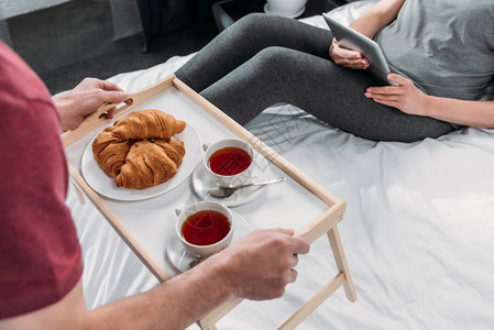 男子带早餐来妇女躺在床图片