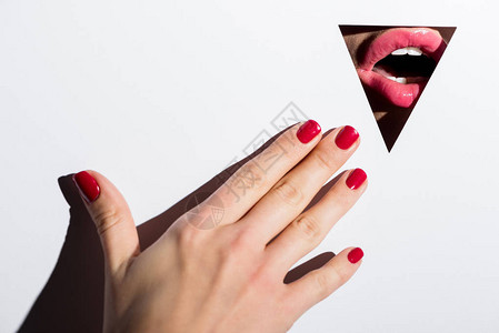 女人用美丽的粉红嘴唇在纸上三角洞后面图片