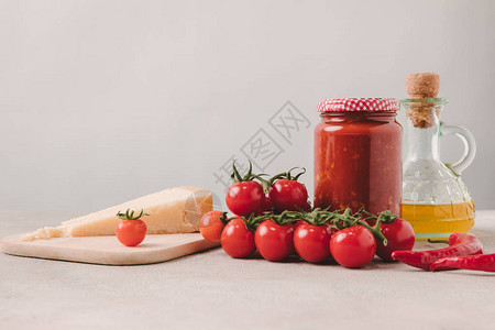 混凝土桌面上的樱桃番茄奶酪番茄酱和橄榄油图片