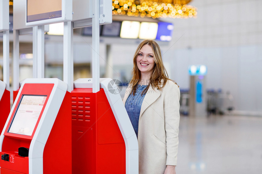 出差回家过圣诞节的年轻女子在国际机场通过电子终端办理登机手续候机楼的女乘客图片
