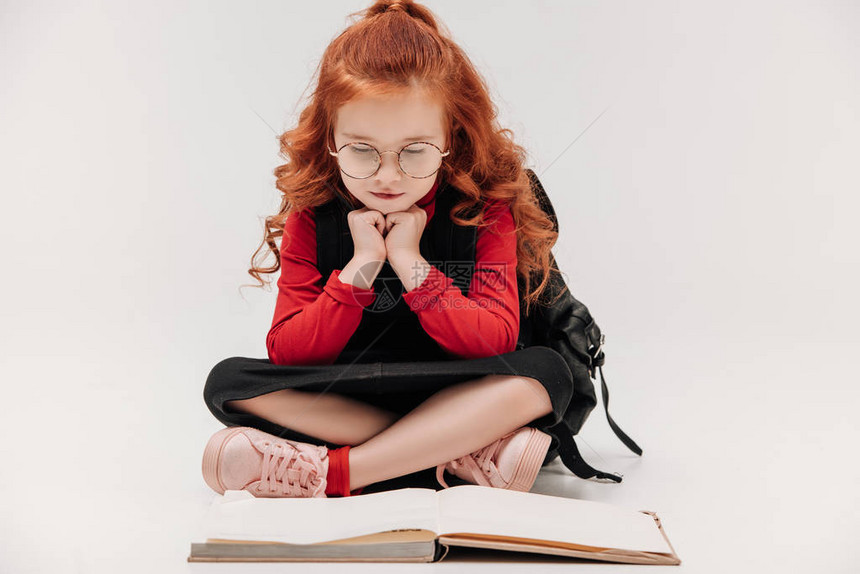 可爱的小女学生在地板上阅读书图片