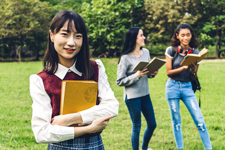 微笑的女国际学生或青少年站着拿书图片