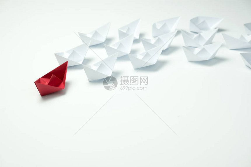 领导力概念由红纸船在蓝背景白舰中领先图片