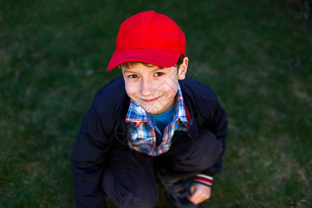 穿红帽子的小男孩在草地图片