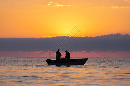 两名渔民在海上乘船捕鱼背图片