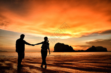 浪漫的情侣在日落时在海滩上手牵图片