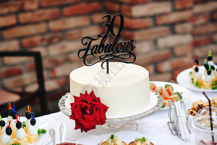 与红玫瑰的生日蛋糕很棒的30岁特别的蛋糕岁户外生日派对上的甜桌带花的图片