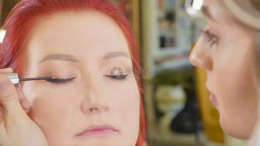 化妆师对模型眼部应用化妆红头模型在编造程序上图片