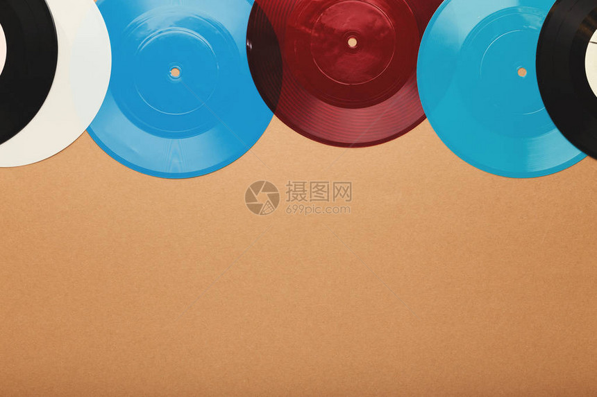 音乐爱好者的创作背景米色表面上旧的蓝色白色和红色老式黑胶唱片的复古媒体板的顶视图片