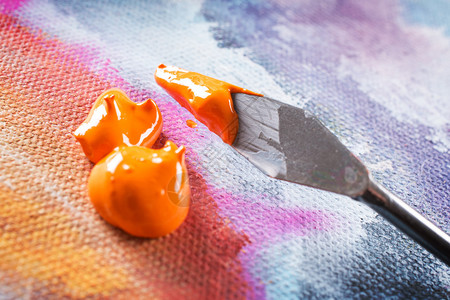 画布上的专业丙烯酸橙色颜料和装载的调色刀图片