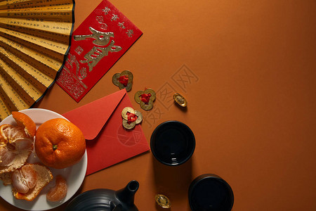 盘上橘子黑茶象形文字风扇金装饰和棕色背景红图片