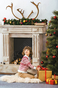 可爱的快乐的孩子坐在地板上与圣诞节图片
