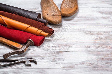色彩鲜艳的皮革卷工作具和鞋楦在白色的木质背景上皮革工背景图片