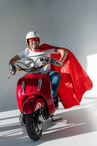 戴保护头盔超级英雄面具和骑红色摩托车的图片