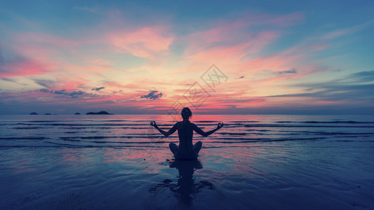 在海洋滩附近做冥想的女人瑜伽剪影图片