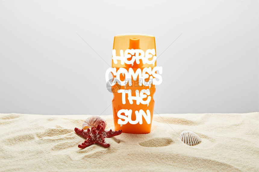 橙色的防晒霜在沙子上用橘色的瓶子和海星图片
