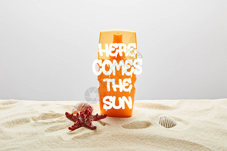 橙色的防晒霜在沙子上用橘色的瓶子和海星图片