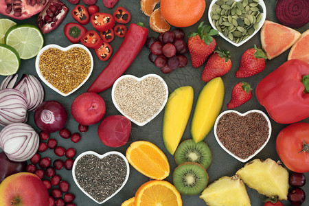 石板背景的心形碗中的水果蔬菜坚果和种子的古饮食健康和超级食物图片