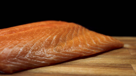 多汁的鲑鱼片的特写镜头多汁的新鲜和红色鲑鱼肉片躺在黑色图片