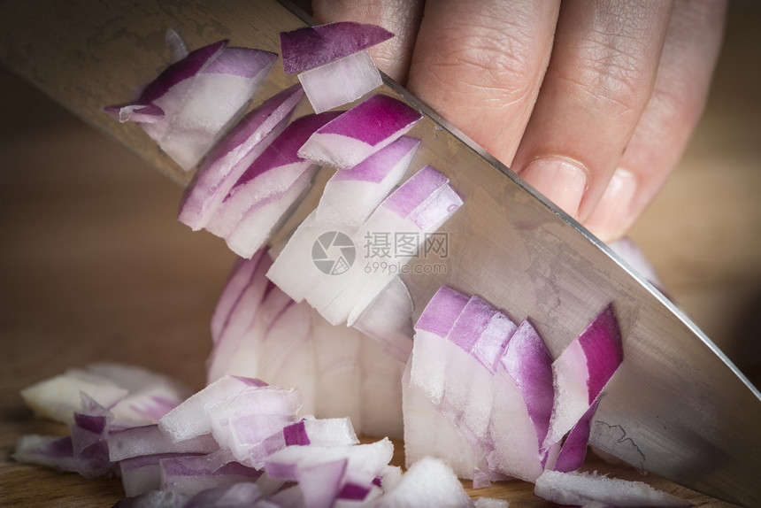 厨师用刀在砧板上切红洋葱图片