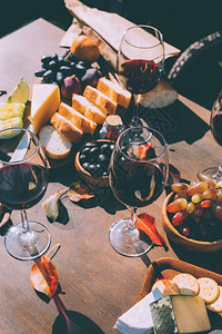 在阳光下的木桌上放着一杯红酒和各种小吃图片