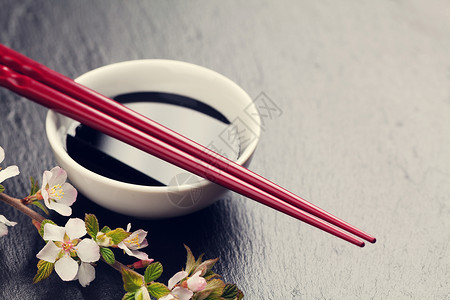 黑石背景的日本寿司筷豆酱碗和樱花带有复制空图片