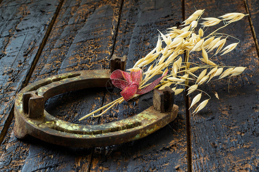 老马蹄和燕麦好运和繁荣的象征老生锈的马蹄铁和燕麦秸秆在深色木制背景上图片