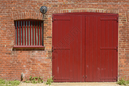 西苏塞克斯州奇切斯特港DellQuay码头楼的旧砖墙上的红漆木制谷仓门和窗户背景图片