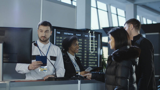 机场检查护照和生物鉴别数据的不同雇员与乘客一起工作图片