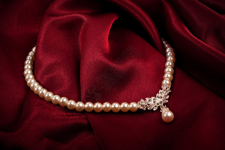 在深红色背景的珍珠项链图片
