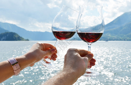 红酒的葡萄酒杯手握在湖对图片