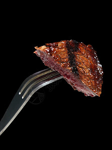 一块烤肉牛排在牛排叉上背景图片