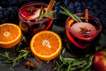 传统的冬季和秋季饮品圣诞节和感恩节鸡尾酒深石上加橙苹果迷迭香肉桂和香料的热葡萄背景图片
